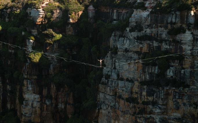 Person climbing a wire over cliff