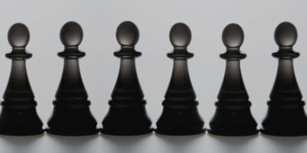 Ten chess pawns first on the left is black followed by one orange pawn then eight black pawns