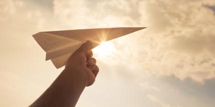 Paper airplane with sky in background
