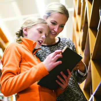Mother with Daughter in Library Reading Book