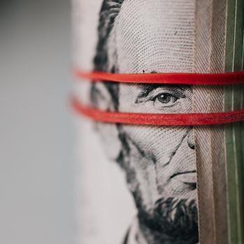 pic of Abe Lincoln money roll with red rubber band around it